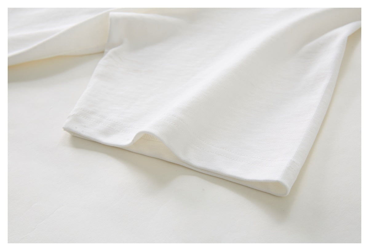 Close-up of the white T-shirt sleeve and stitched hem, laid flat.