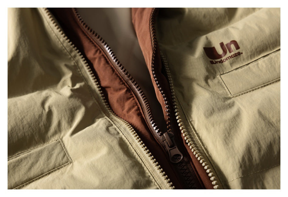 Close-up of an open khaki jacket showing its rust-colored lining and two zippers.