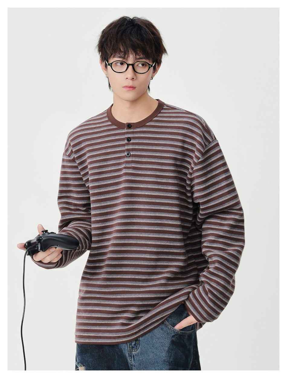 Model wearing a brown and gray striped long-sleeve henley with a three-button placket.