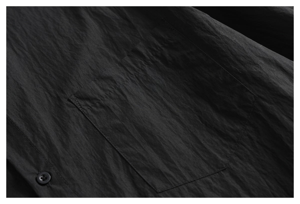 Close-up of a black shirt's chest pocket and a button on the front.