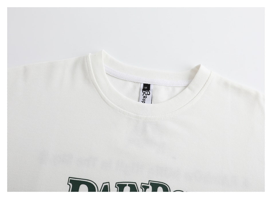 Close-up of an off-white T-shirt neckline and upper chest, with part of a dark green print visible.