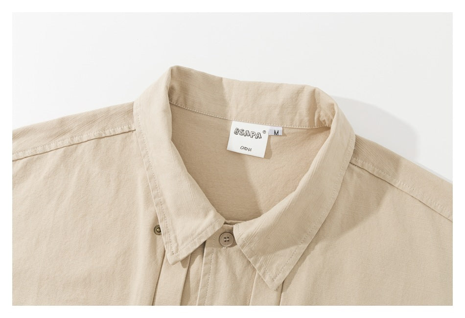 Close-up of a beige shirt collar, front placket, and sewn neck label.