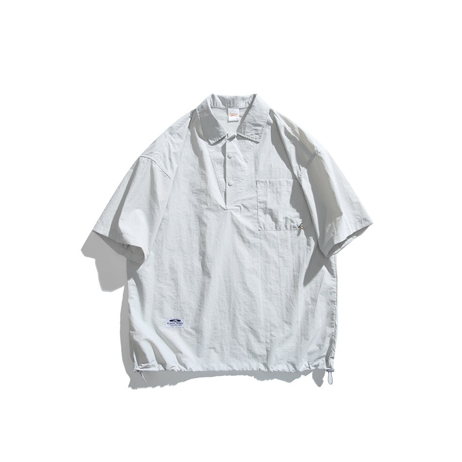 White-gray short-sleeve pullover shirt with collar, snap placket, chest pocket and drawcord hem, flat lay