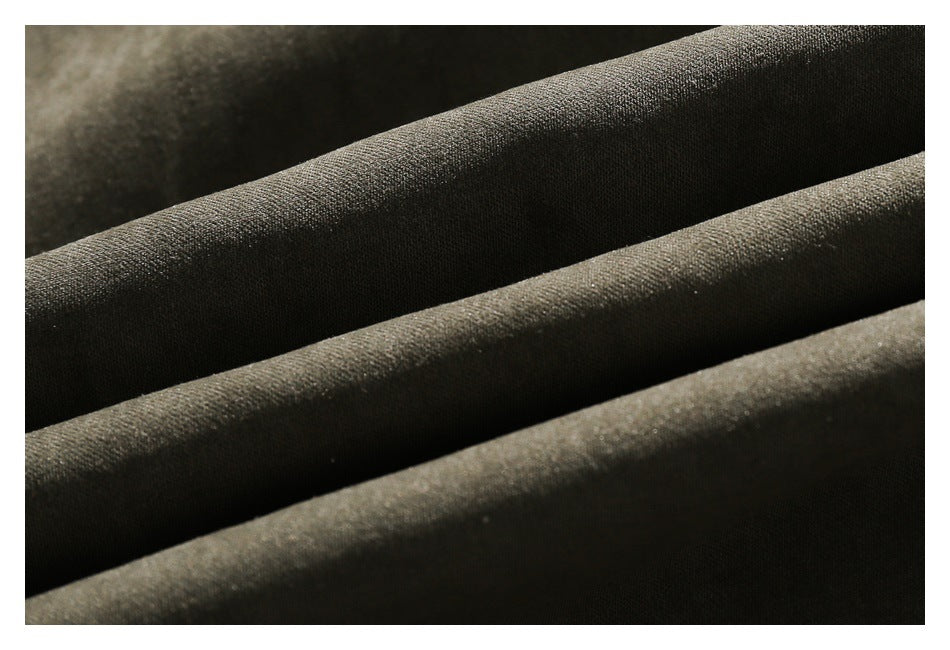 Extreme close-up of dark olive fabric arranged in soft folds, showing its surface texture.