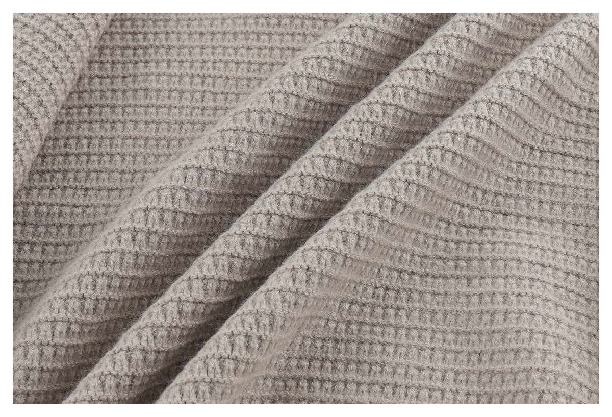 Close-up showing the taupe cardigan's raised, grid-like knit texture and draped folds.