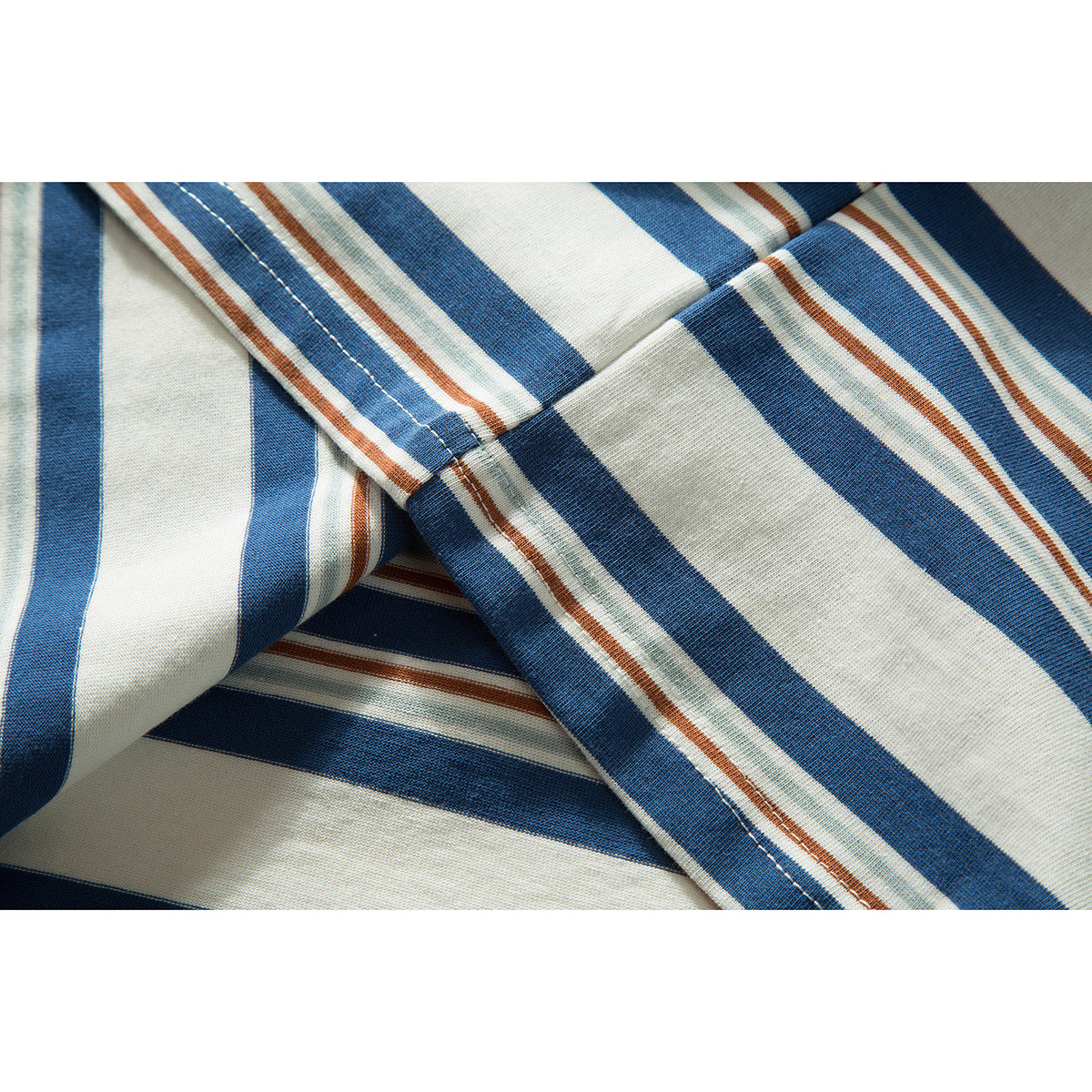 Close-up of striped fabric showing a stitched seam in cream, blue, rust, and pale green.