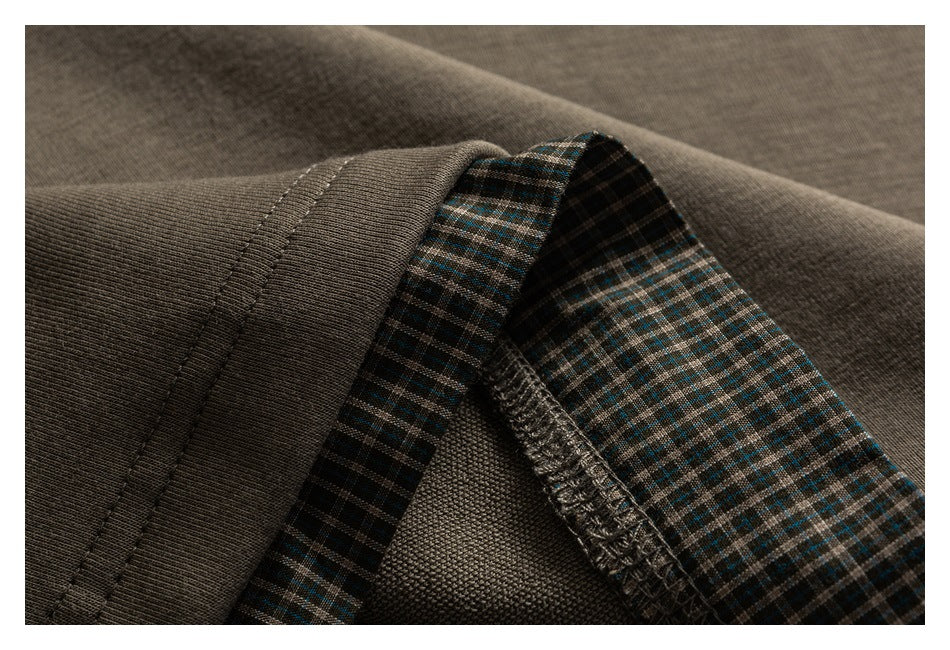 Close-up of a garment edge with dark brown-gray fabric and blue-brown plaid lining.