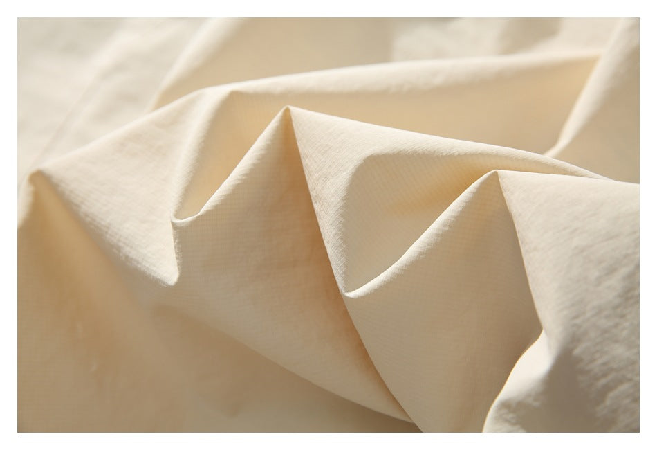 Close-up of the light beige jacket fabric, showing its fine texture and folded surface.