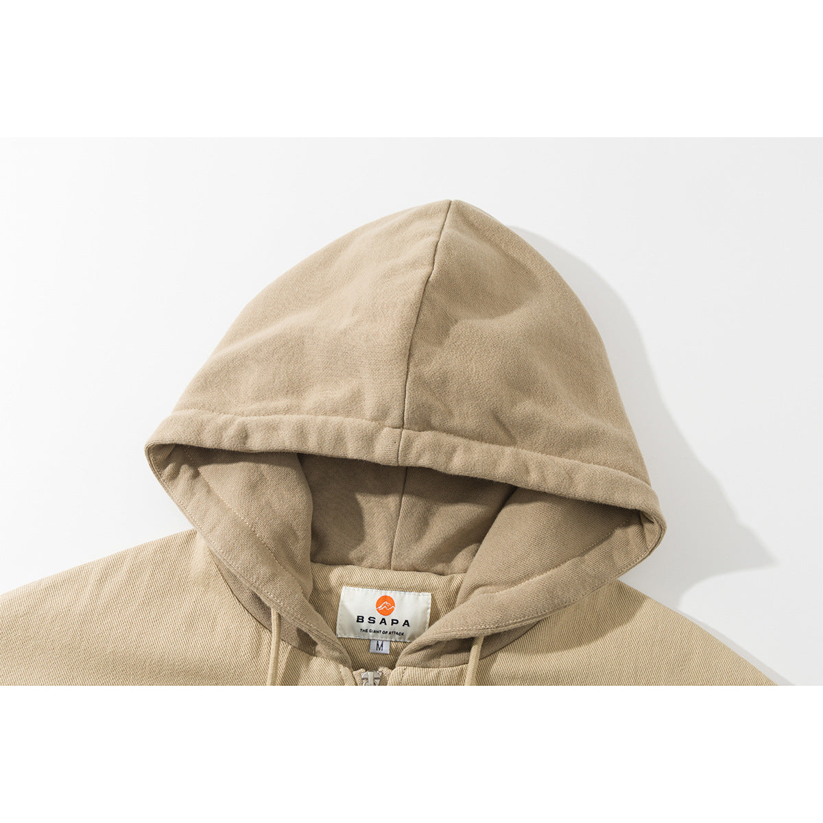 Close-up of a beige hooded jacket showing the hood seams, drawstrings, and neck label.