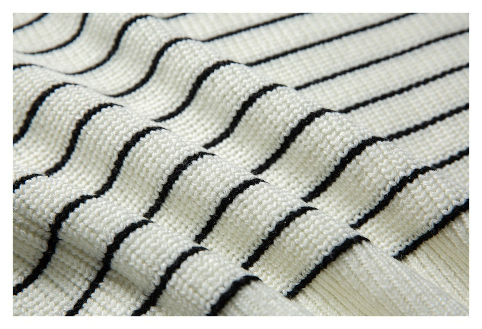Textured close-up of ivory knit fabric with narrow black stripes draped in folds.