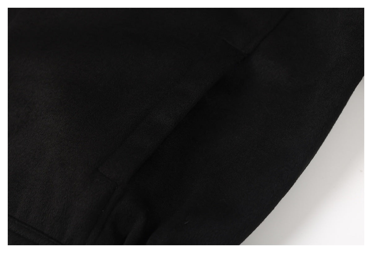 Close-up of black garment fabric with a seam and folds against a white background.
