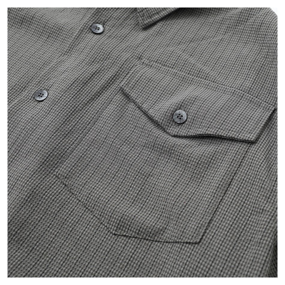 Close-up of a gray micro-check shirt front, showing buttons and a buttoned chest pocket.
