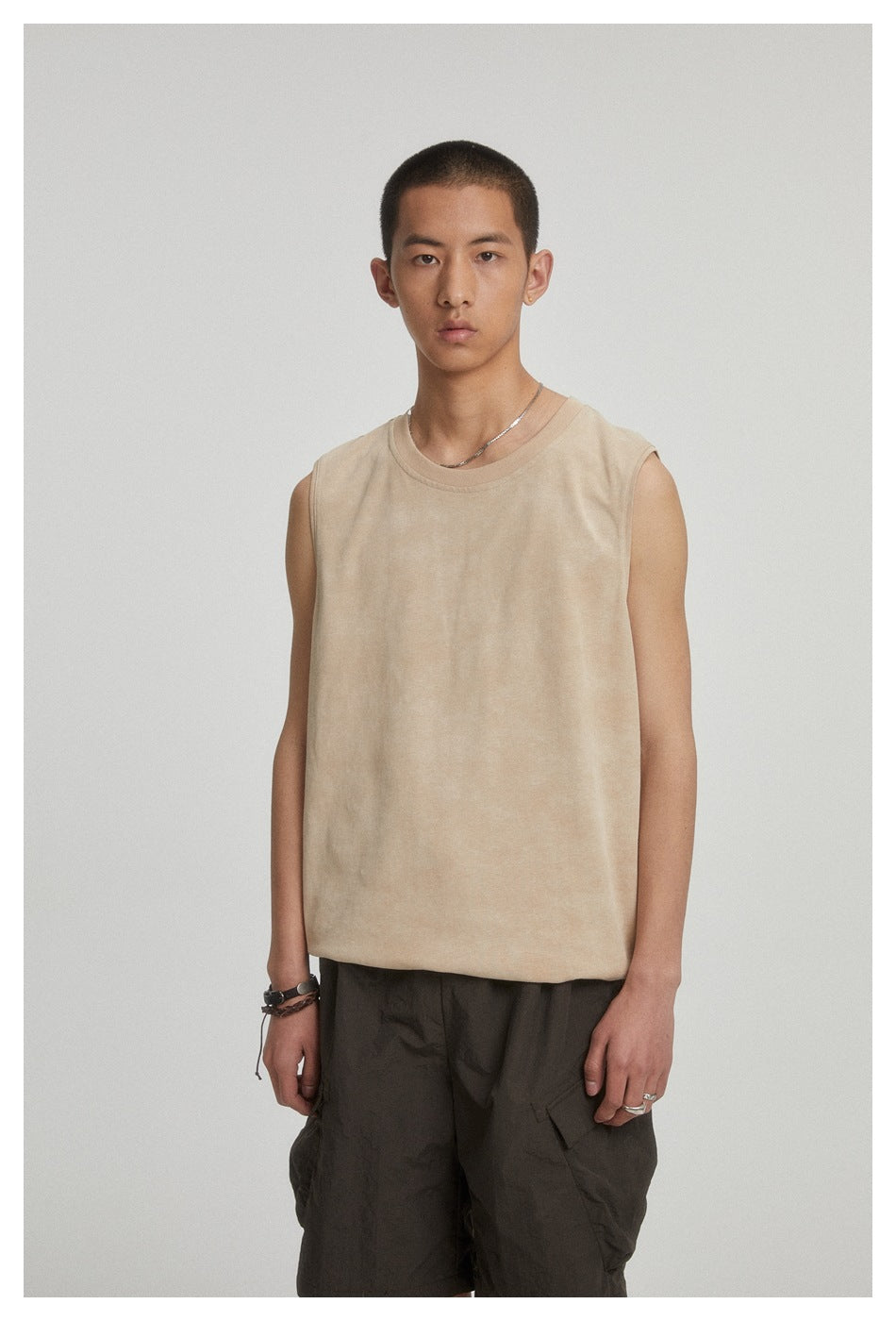 Model wearing a beige sleeveless crewneck top with dark cargo shorts, shown from the front.