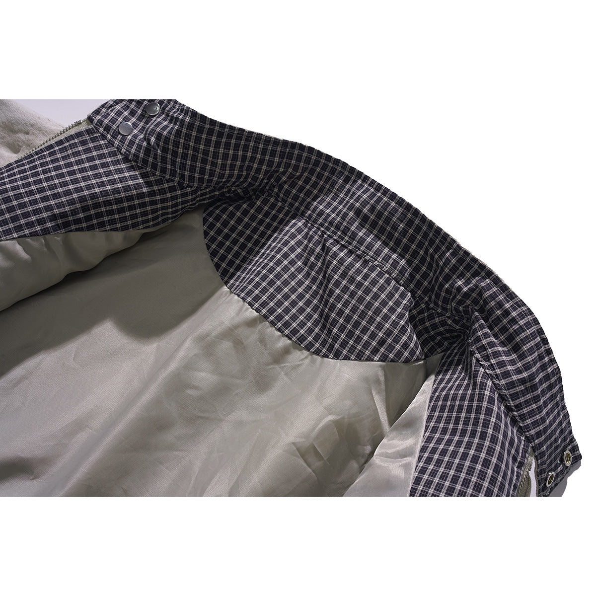 Inside view of a jacket showing dark plaid lining, pale inner fabric, and fastening buttons.