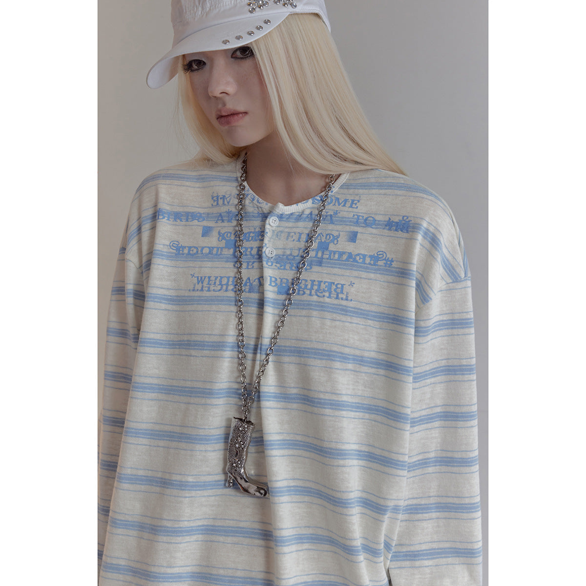 Close view of a model wearing a cream-and-blue striped button-front top with blue chest lettering.