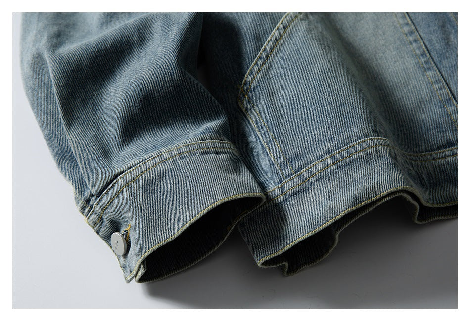 Close-up of a blue denim jacket cuff with yellow topstitching and a small metal button.