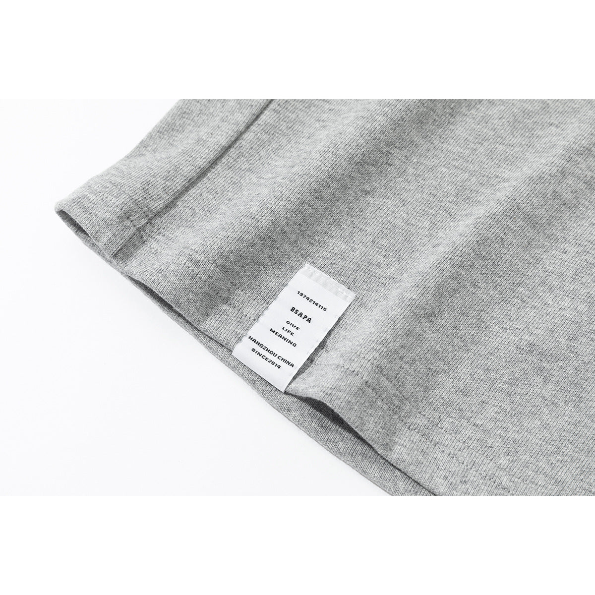 Close-up of the hem of a heather-gray shirt with a small sewn-in English text label.