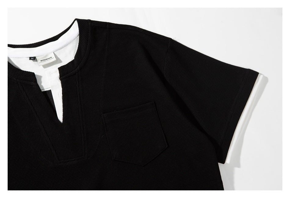 Close-up of the black shirt's notched neckline, chest pocket, and short sleeve.
