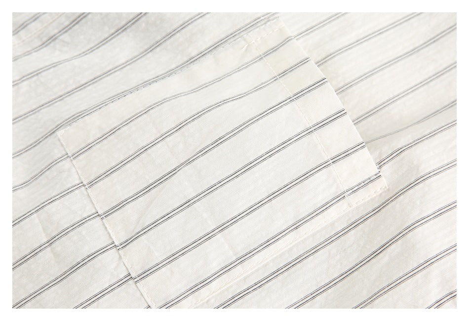Close-up of a cream garment's rectangular patch pocket with thin dark stripes.