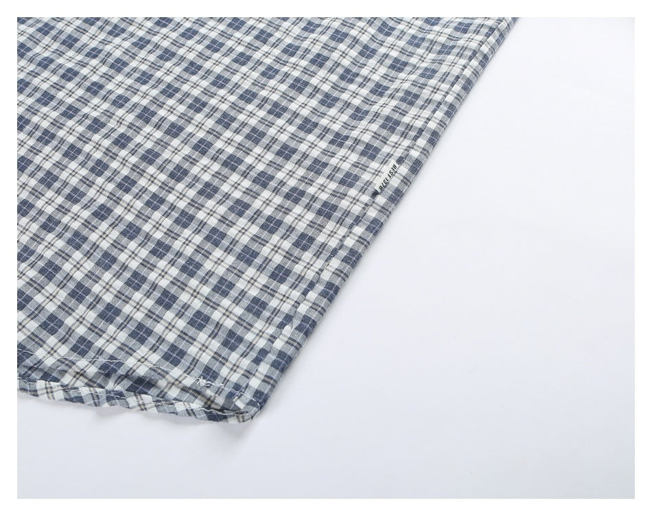 Close-up of the lower edge of a plaid shirt, with a small text label on the fabric.