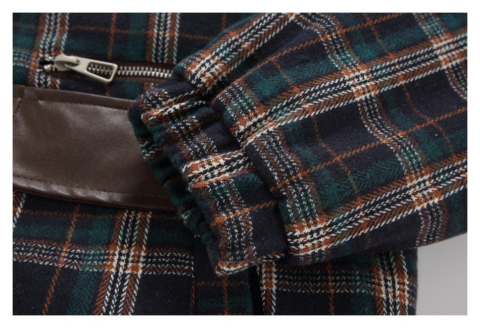 Close-up of a plaid sleeve cuff folded over the garment beside a brown trim panel and zipper.