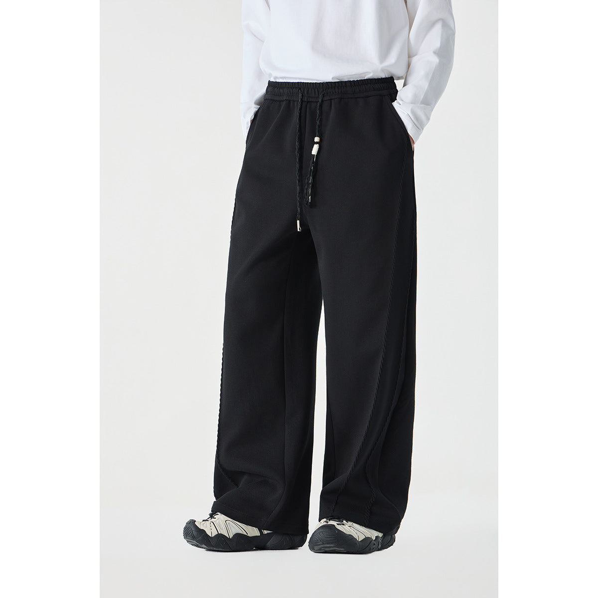 Front view of a model wearing black wide-leg drawstring pants with a white top.
