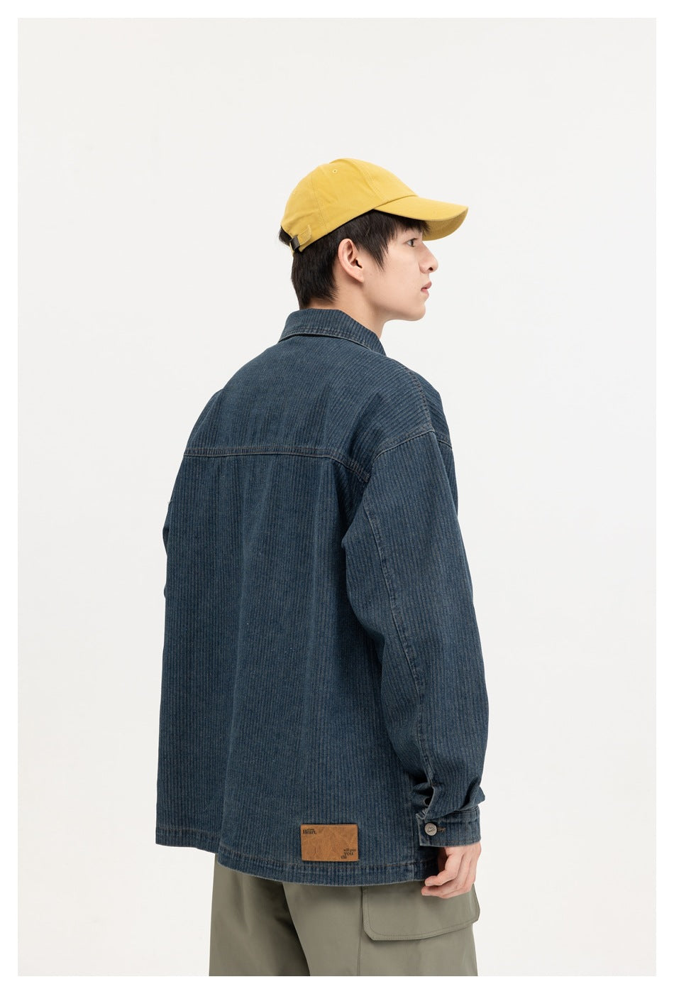 Model wearing a dark blue textured denim jacket, shown from the back in a three-quarter view.