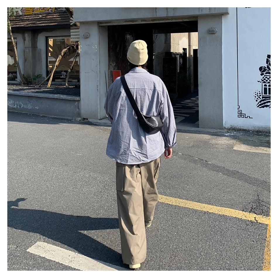 Rear view of person wearing khaki wide-leg cargo pants with striped shirt and black crossbody bag outdoors