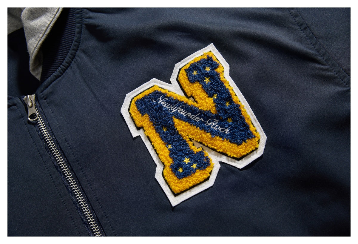 Close-up of a blue-and-gold embroidered letter patch on the chest of a dark navy jacket.