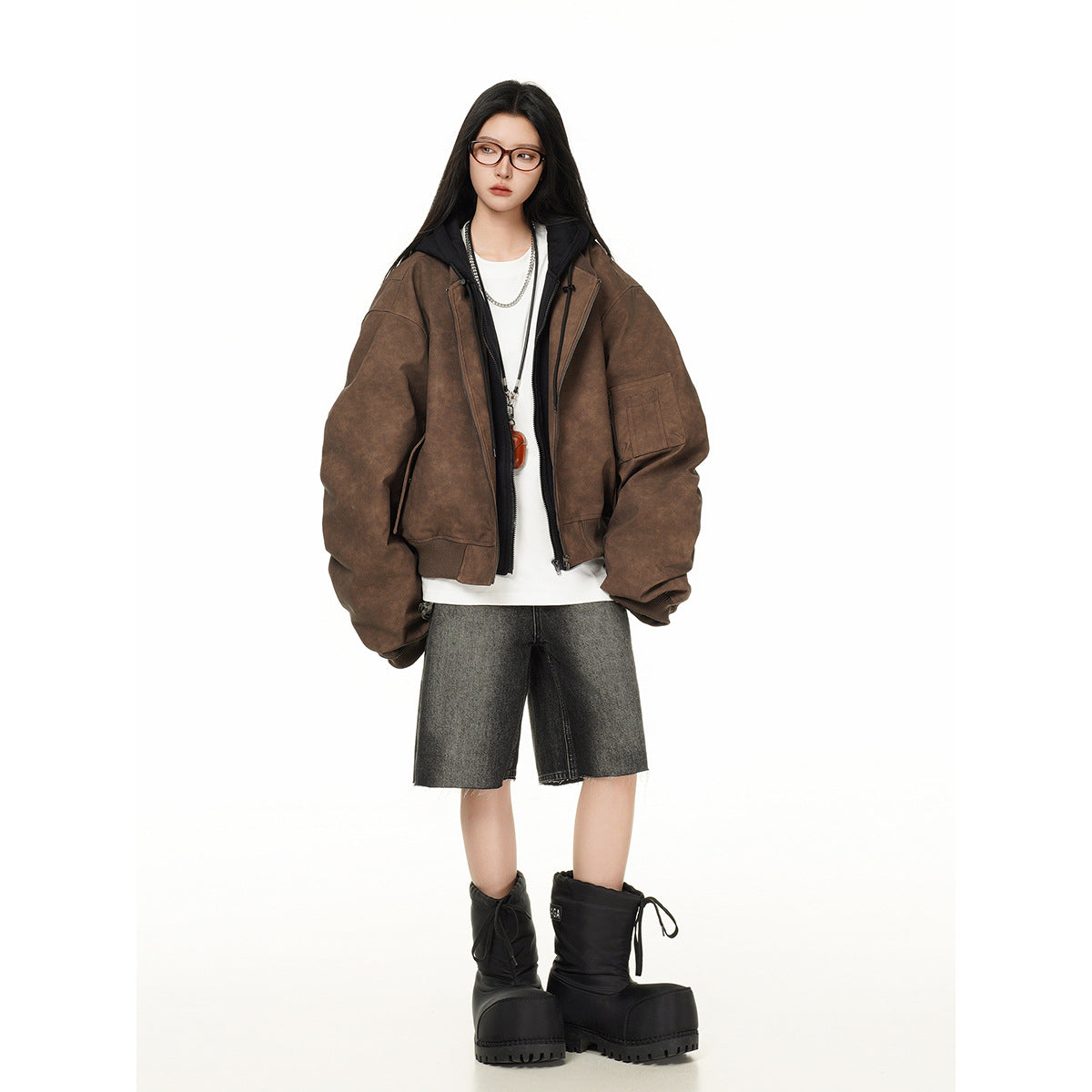 Model wearing an oversized brown zip-front jacket with a black hood, layered over a white top.