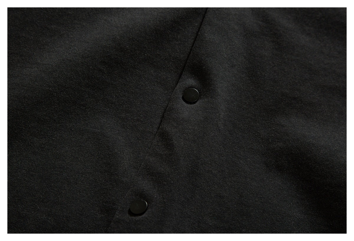 Close-up of the dark shirt front placket with two black snap buttons.