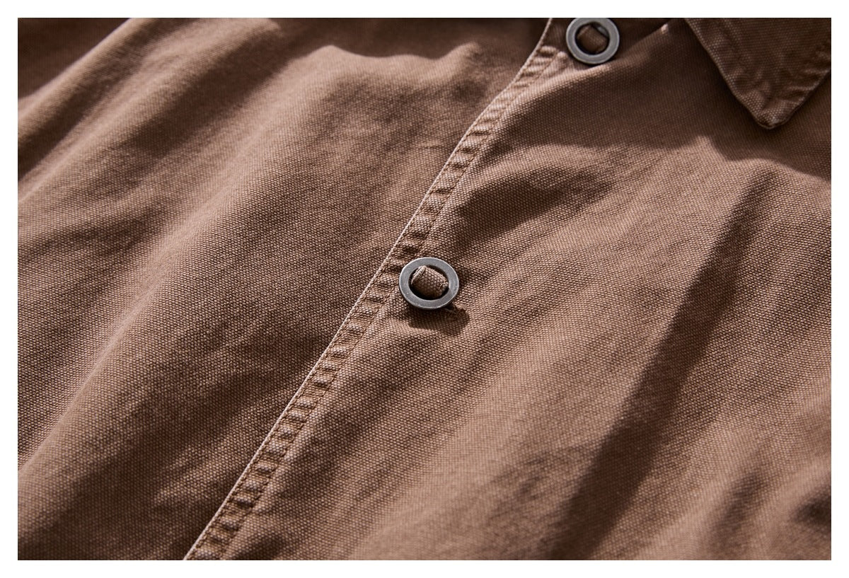 Close-up of brown jacket fabric, stitched front placket, and dark ring-style buttons.