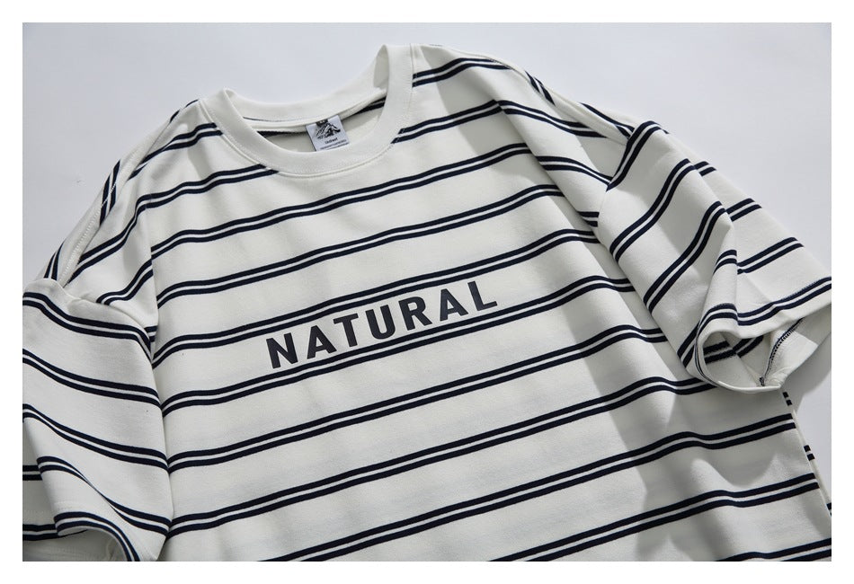 Flat-lay view of an ivory long-sleeve crewneck shirt with navy horizontal stripes and “NATURAL” across the chest.