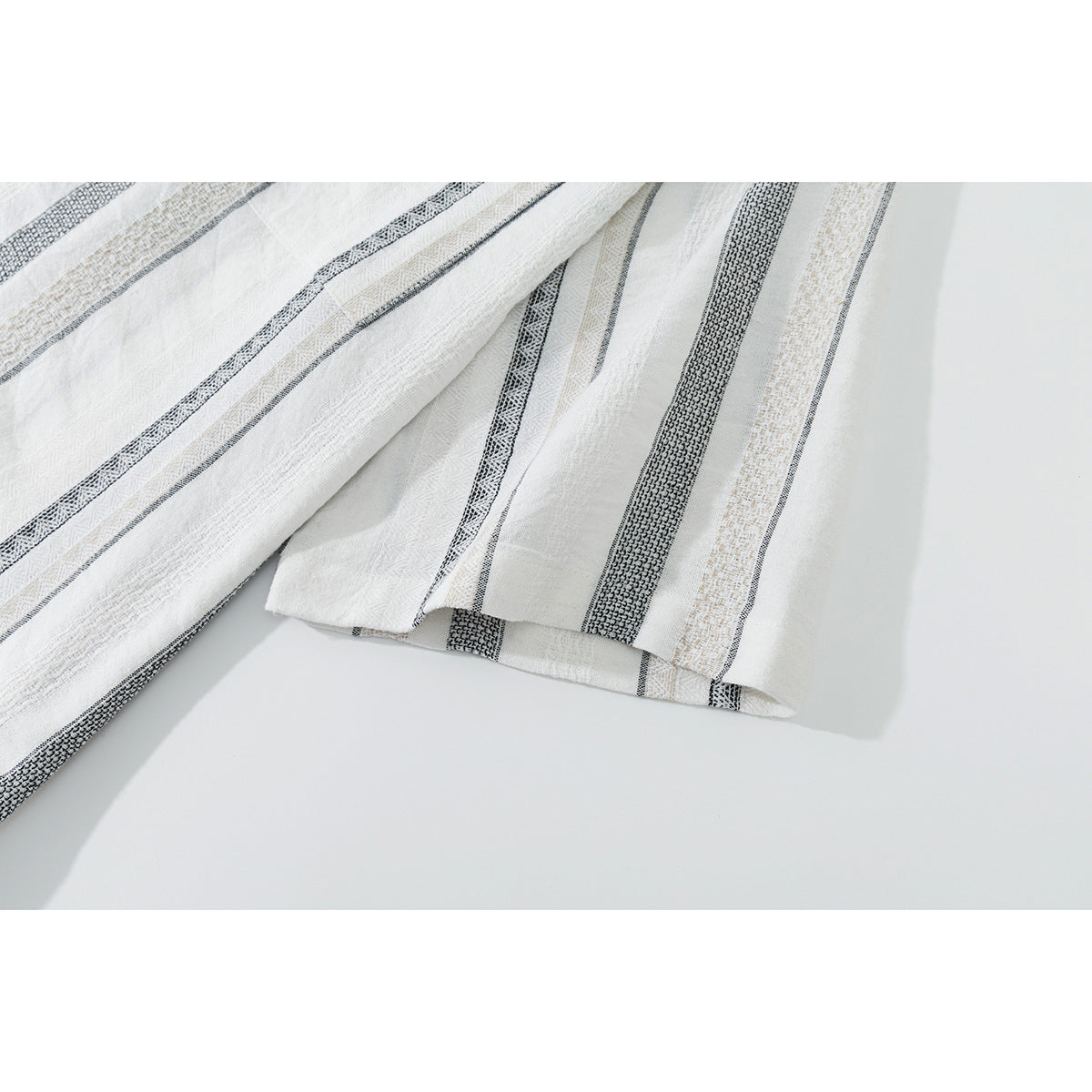 Close-up of the white shirt's short sleeve and hem with black and beige stripes.