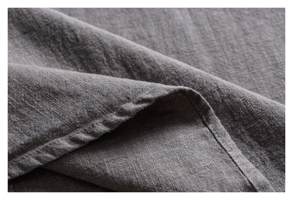 Close-up of folded gray woven fabric showing its fine texture and stitched edge.