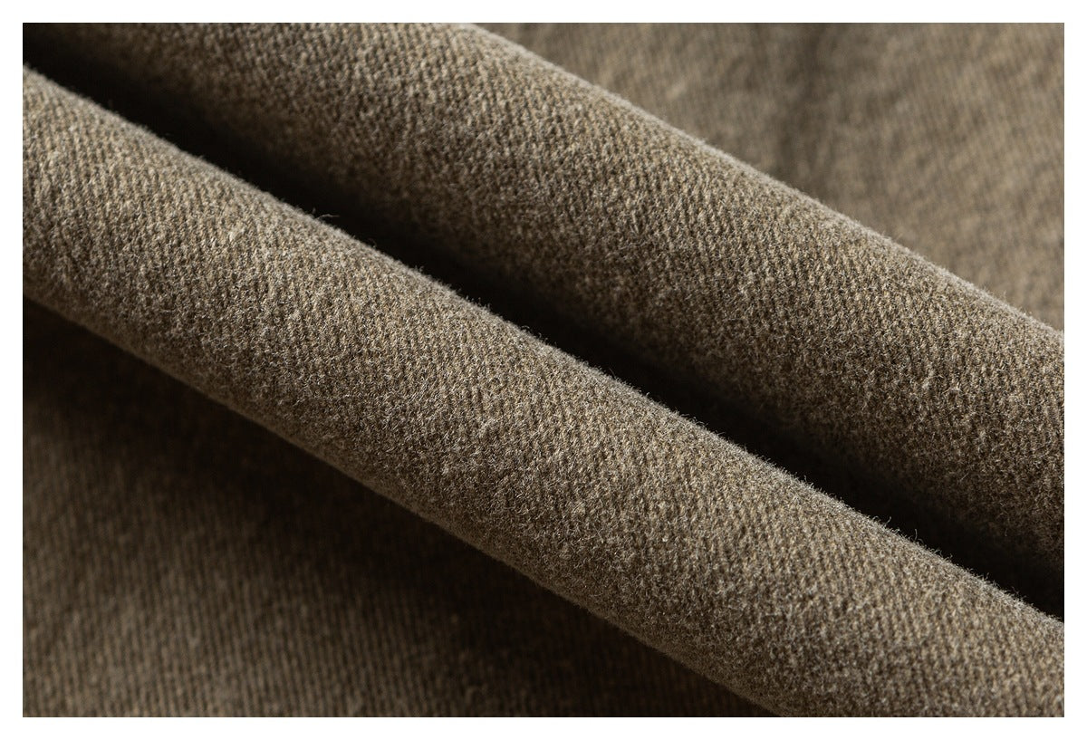 Macro view of the textured tan-brown garment fabric folded into soft ridges.