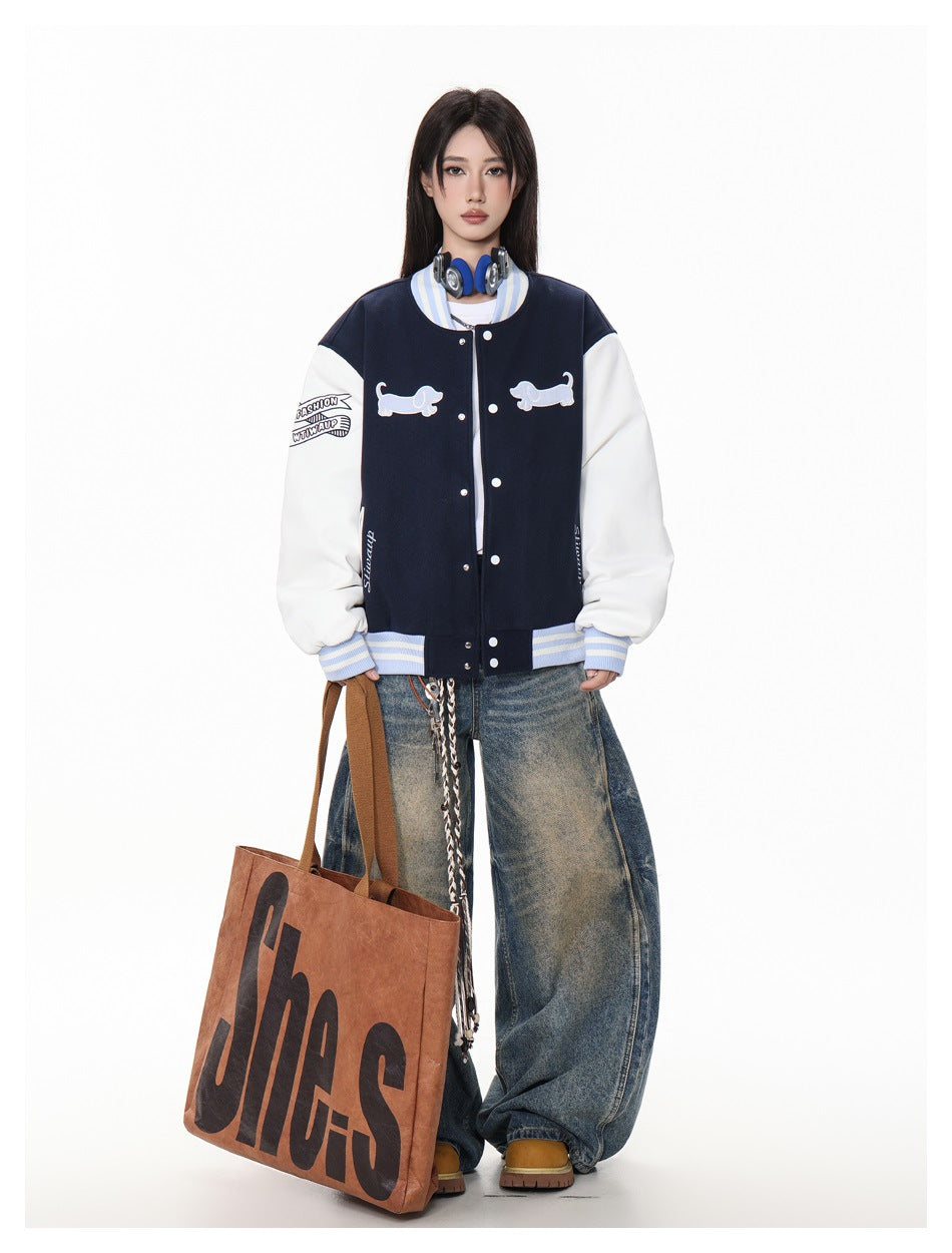 Model wearing a navy and white varsity jacket with dachshund appliqués, wide-leg jeans and a large brown tote bag