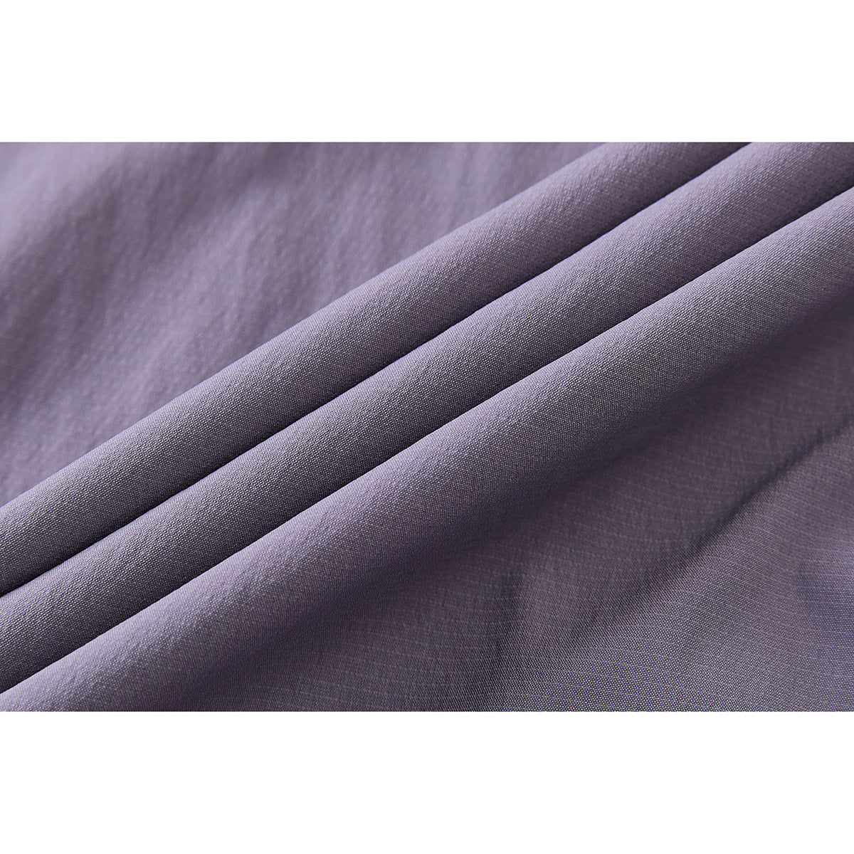 Close-up of muted lavender fabric draped in folds, showing its fine woven texture.