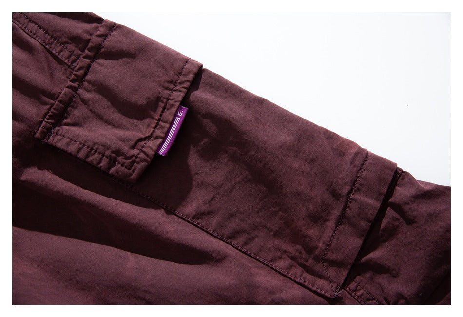 Close-up of a burgundy cargo pocket flap with a small purple fabric tab and visible stitching.