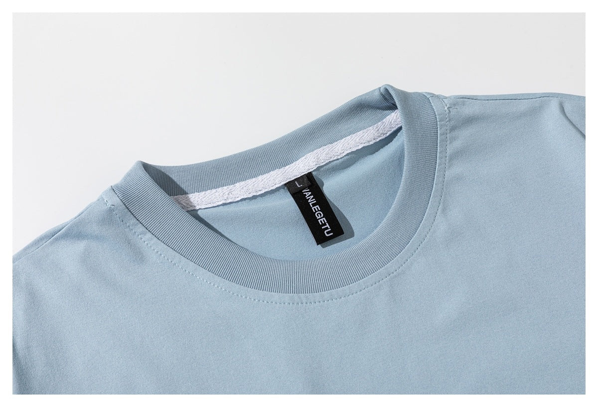 Close-up of a light blue T-shirt's ribbed crew neckline, inner seam, and black neck label.