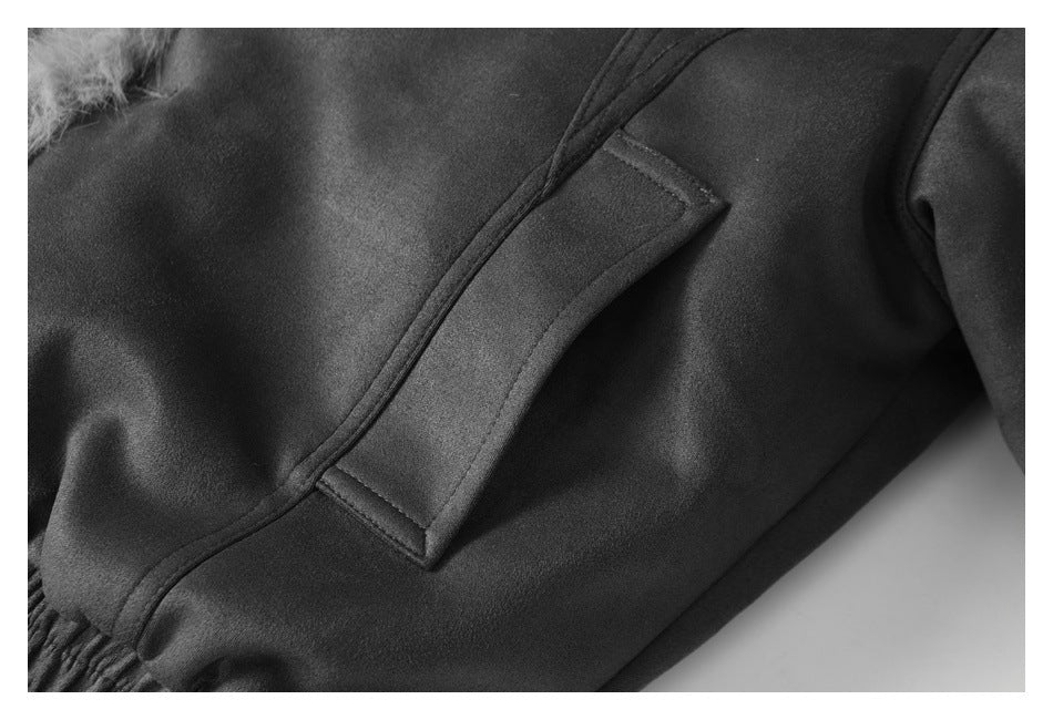 Close-up of a dark charcoal garment showing a flap pocket, seams, and a small fur-trimmed edge.