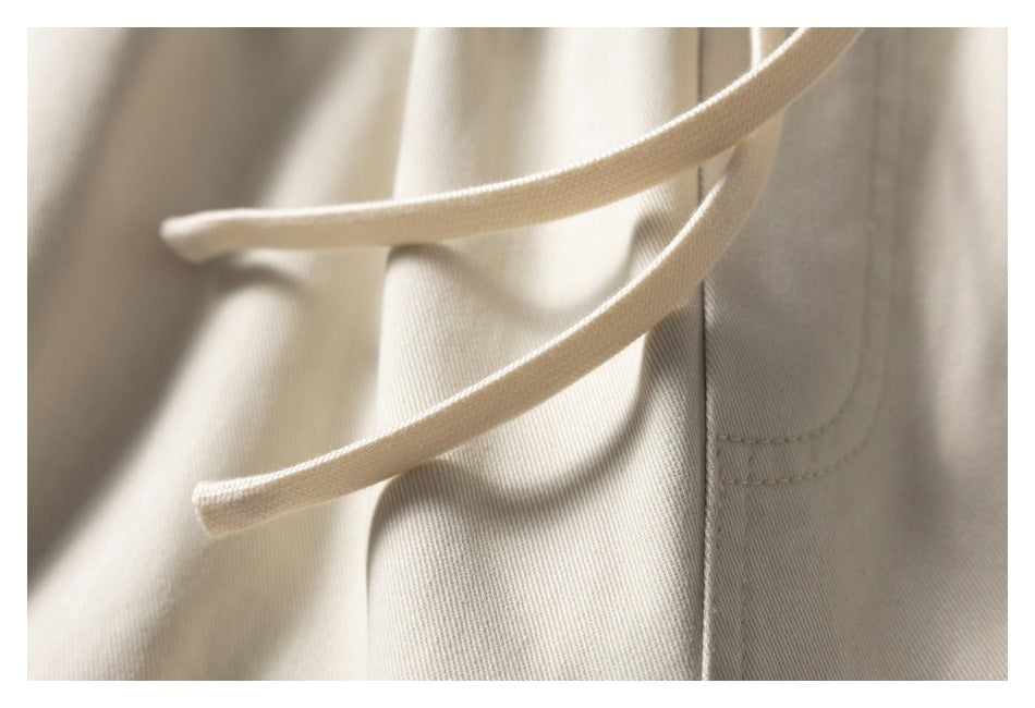 Close-up of two light beige drawstrings and stitched seams on the shorts.