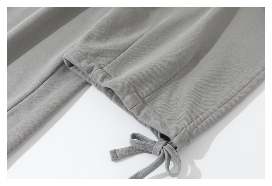 Close-up of a gray sweatpant leg hem with a tied drawstring detail.