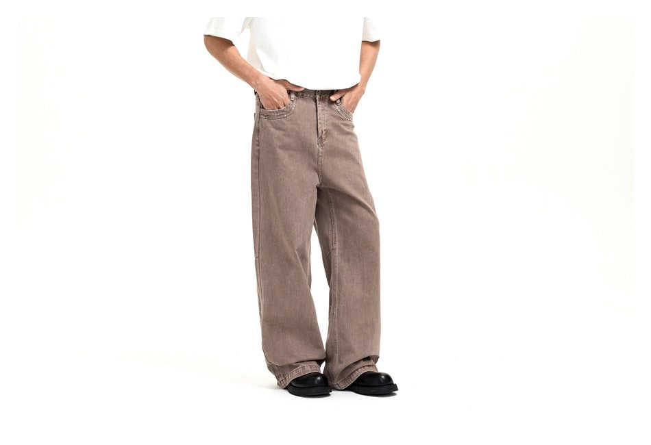 Angled front view of a model wearing loose taupe jeans with a button fly and wide legs.