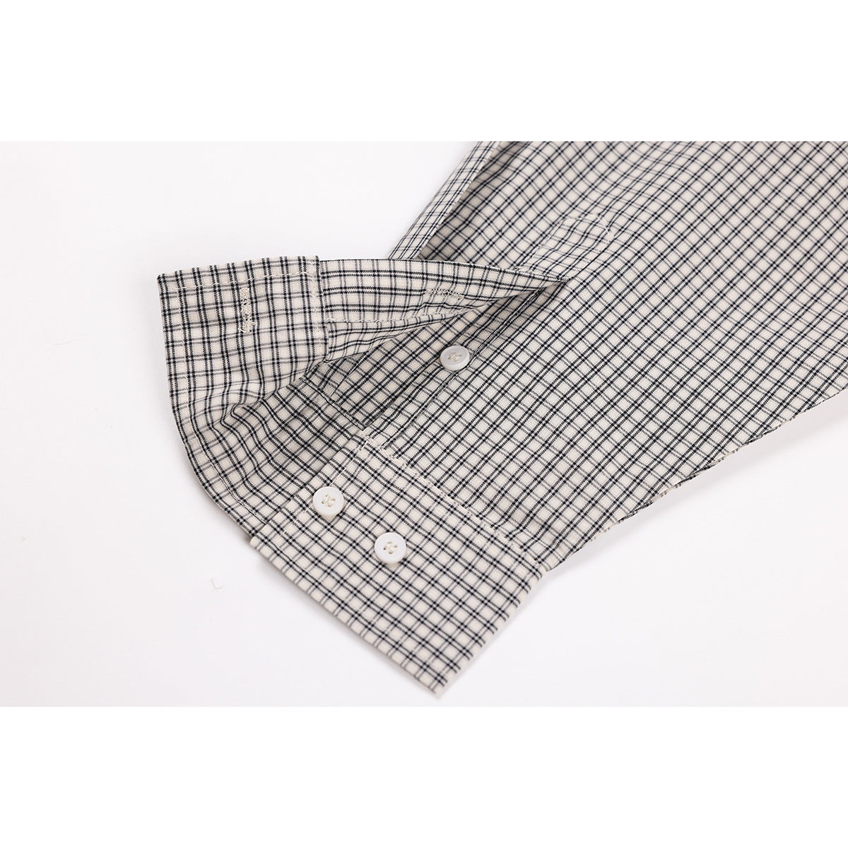 Close-up of the checked shirt's buttoned cuff and sleeve placket on a white background.