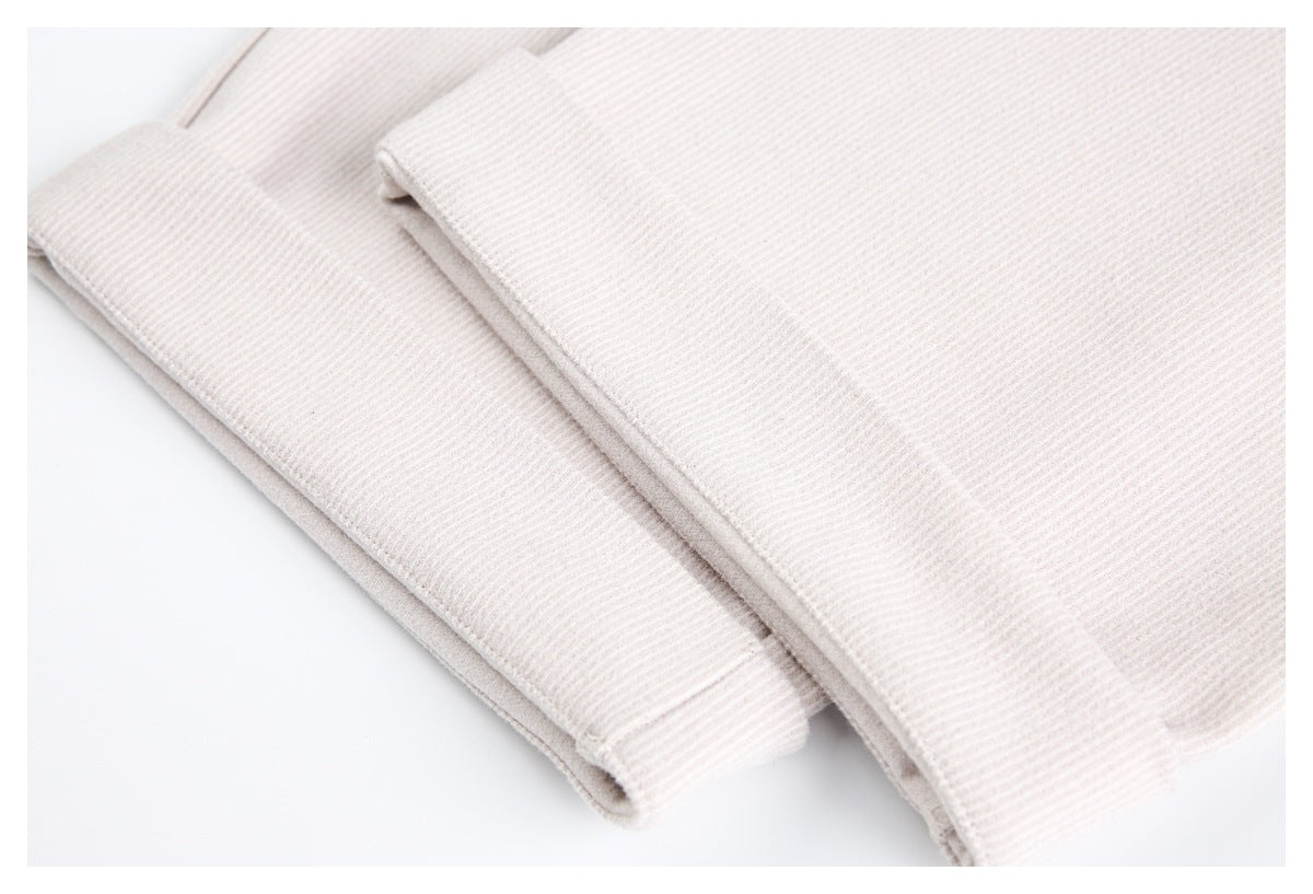 Folded sections of pale beige ribbed trousers shown close up.