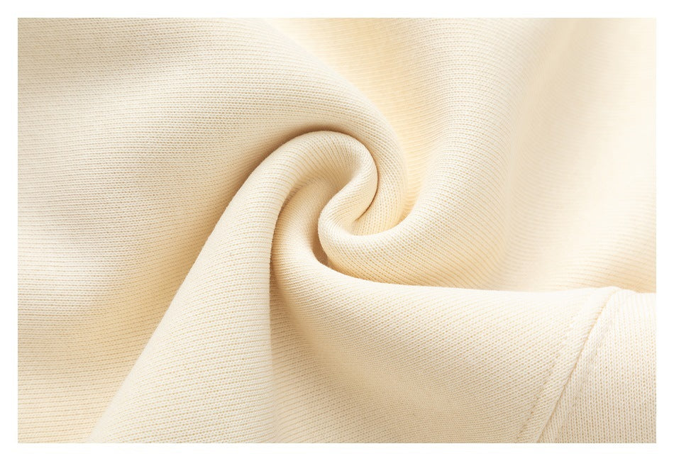 Close-up of ivory knit fabric draped into soft folds, showing its fine ribbed texture.