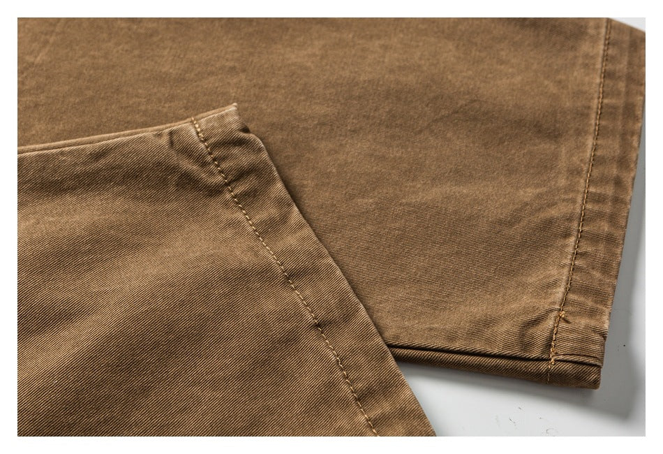 Close-up of brown trouser leg fabric and finished hem on a white background.