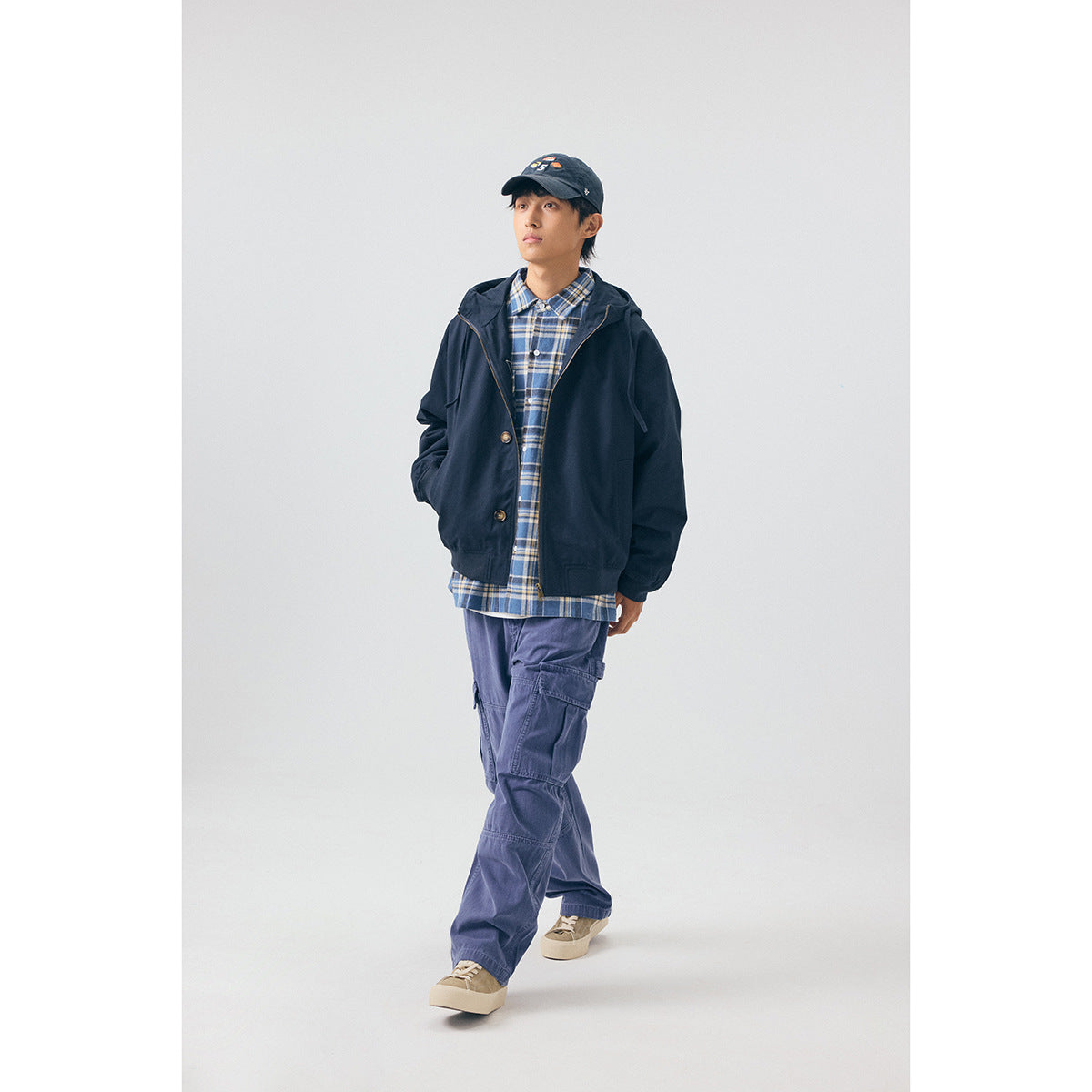 Full-length model wearing a navy hooded jacket over a blue plaid shirt and purple cargo pants, shown from the front.