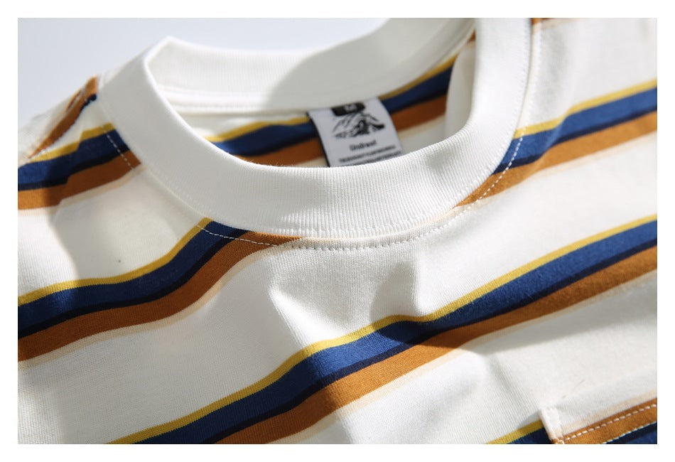 Close-up of the cream T-shirt’s ribbed crew neckline and blue, rust, and yellow stripes.